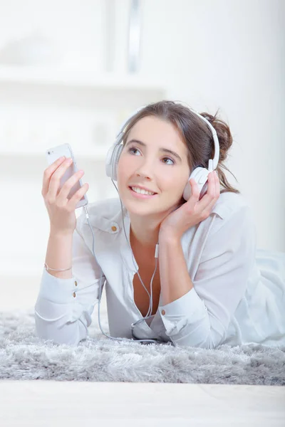 Dama acostada en la alfombra, escuchando auriculares — Foto de Stock