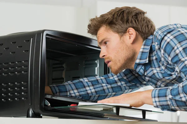 Jovem reparador masculino fixação forno na cozinha — Fotografia de Stock