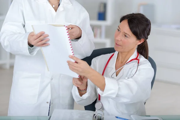 Atractiva doctora consultando a una coleague en el consultorio médico — Foto de Stock