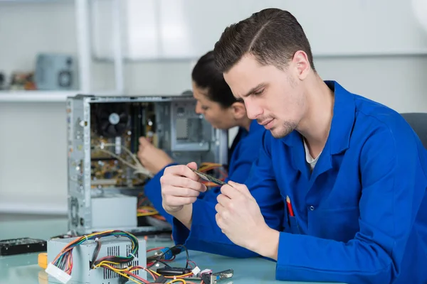 Equipe de estudantes examinando e reparando peças de computador — Fotografia de Stock