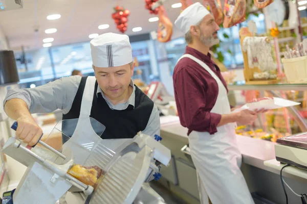 Twee mannen aan het werk achter balie in delicatessen — Stockfoto