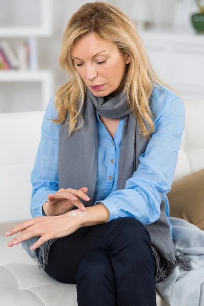 Vrouw verspreiding crème op haar hand — Stockfoto