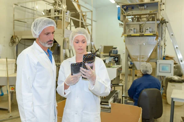 Hombre y mujer en fábrica comparando productos — Foto de Stock