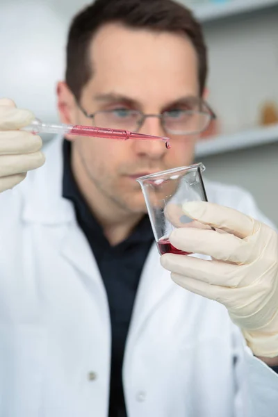 Scientifique en laboratoire tenant une pipette et une éprouvette — Photo