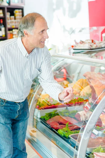 Uomo che punta al prodotto nel banco della carne — Foto Stock