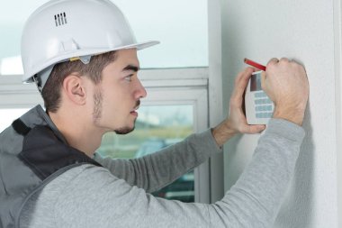 worker installing alarm system in office clipart