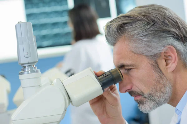 Hombre maduro mirando al microscopio —  Fotos de Stock