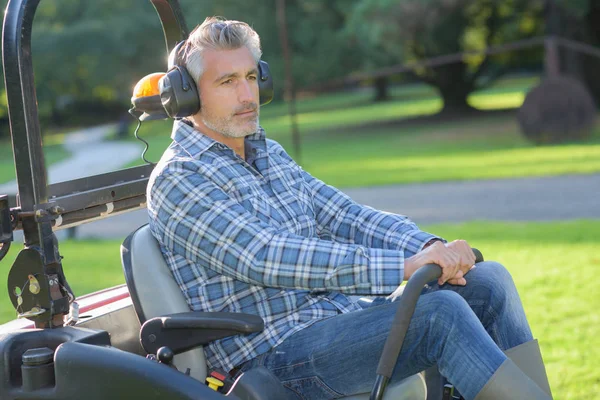 Homem usando um sentar no cortador de grama — Fotografia de Stock