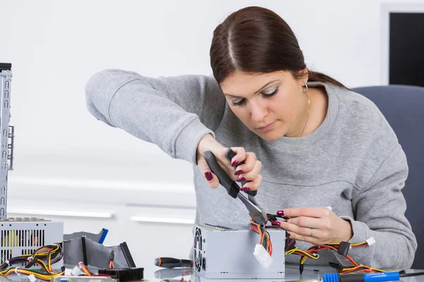 Senhora trabalhando no computador com alicate — Fotografia de Stock