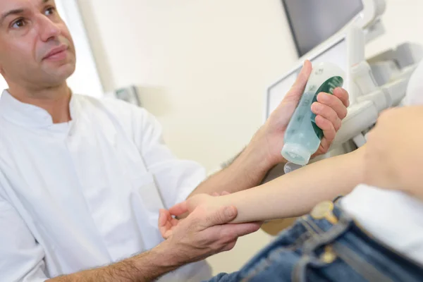 Médico aplicando gel lubrificante no braço do paciente — Fotografia de Stock