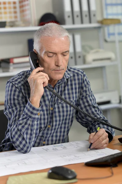 Starší muž při volání u svého pracovního stolu — Stock fotografie