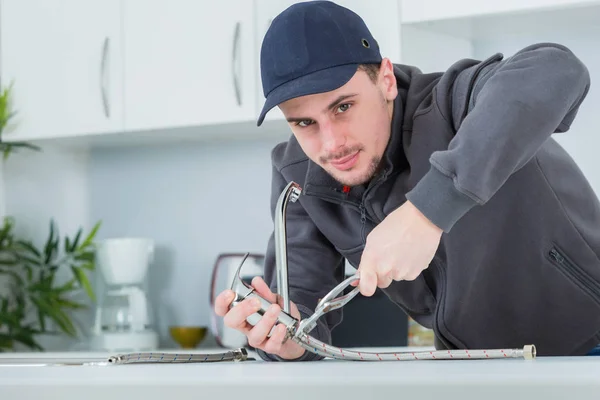 Knappe jonge loodgieter vaststelling van tap op cleints thuis — Stockfoto