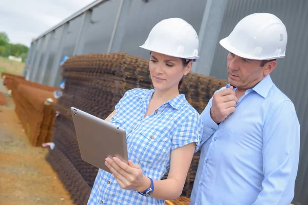 Två arbetare i hardhats tittar på surfplatta — Stockfoto