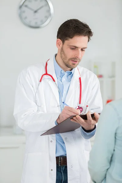 Läkare tar anteckningar att diagnostisera patientens — Stockfoto