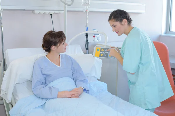 Медсестра показывает пациенту управление больничной койкой — стоковое фото