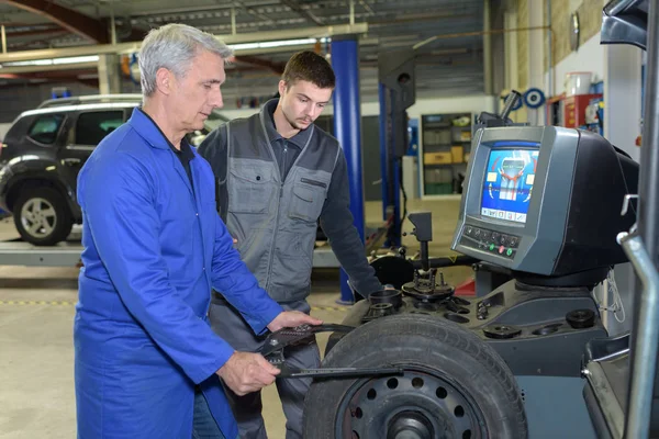 Apprenti mécanicien et enseignant roue de rechapage dans l'atelier automobile — Photo