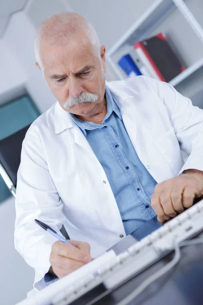 Senior doctorscientist scrivendo sul lavoro — Foto Stock