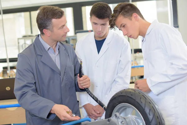 Teacher and students looking at wheel — Stock Photo, Image