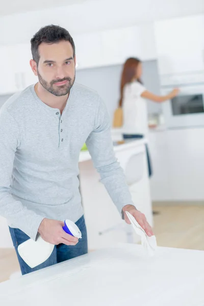 Homem limpeza mesa de cozinha com spray — Fotografia de Stock