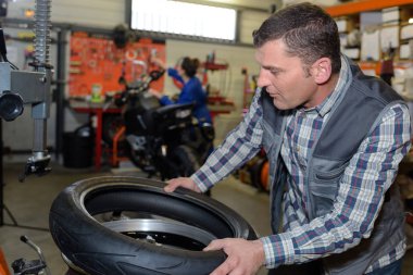 Mechanic holding scooter tyre clipart