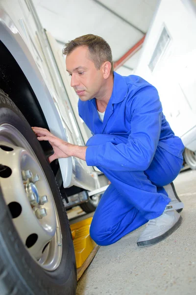 Mechanic assessing tyres on van — Stock Photo, Image
