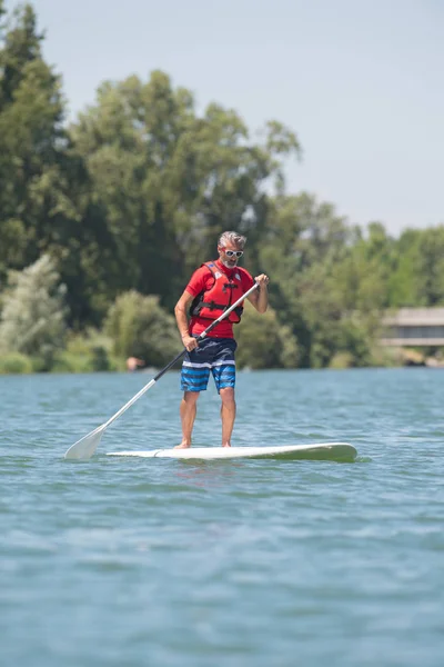 Człowiek cieszyć jazdą na jeziorze z paddleboard — Zdjęcie stockowe