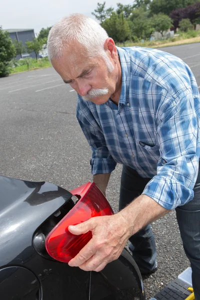 Oude man installeert staart licht op het voertuig — Stockfoto