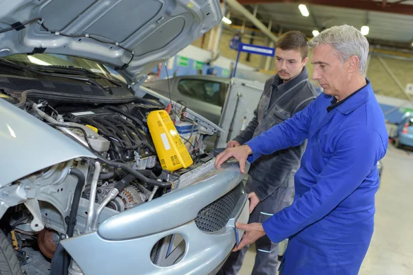 Student met instructeur die een auto repareert tijdens het leerlingwezen — Stockfoto