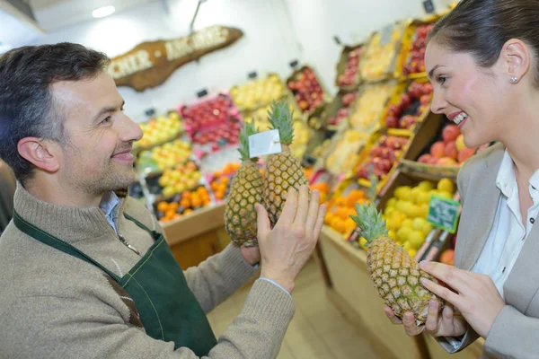 Mujer sonriente eligiendo diferentes frutas en la exhibición de la tienda de alimentos de granja —  Fotos de Stock