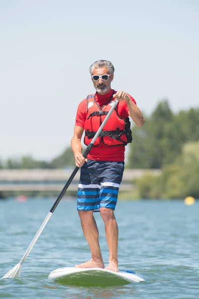 Uomo godendo di un giro sul lago con paddleboard — Foto Stock