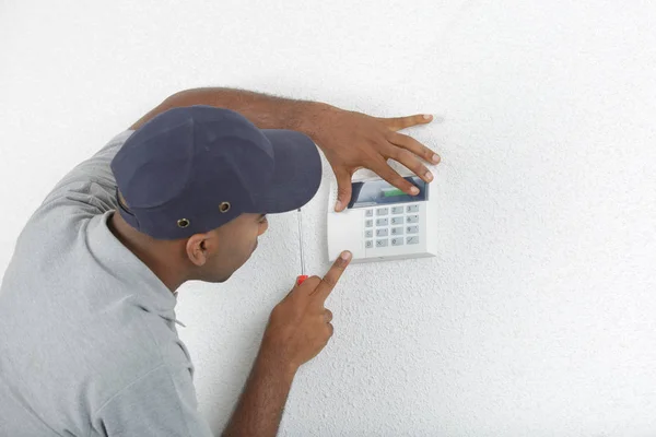 Hombre que ajusta el teclado eléctrico a la pared —  Fotos de Stock