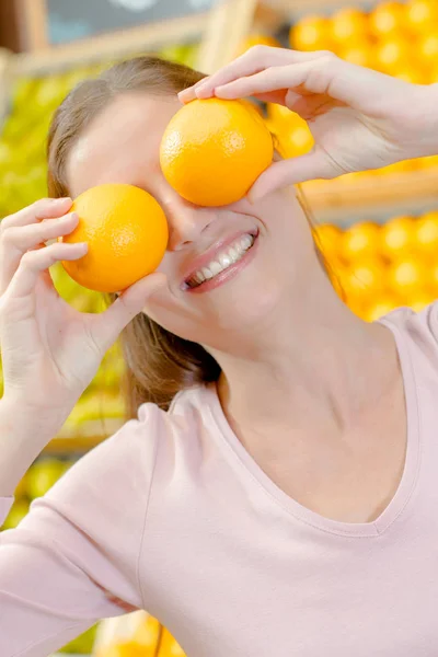 Senhora segurando laranjas sobre seus olhos — Fotografia de Stock