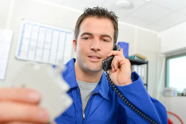 Hombre en el teléfono, sosteniendo componente eléctrico desenfocado — Foto de Stock