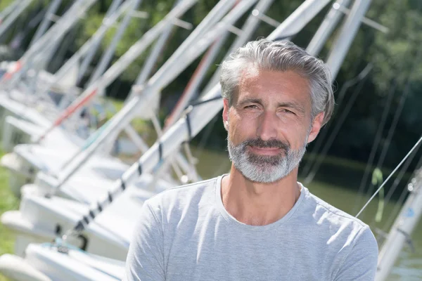 Homem bonito posando na frente de barcos à vela e lago — Fotografia de Stock