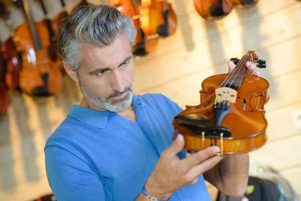 Homem que inspeciona violino e homem — Fotografia de Stock