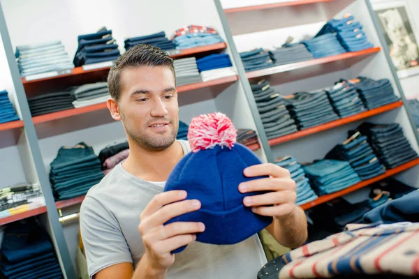 Man tittar på bobble mössa i butik — Stockfoto