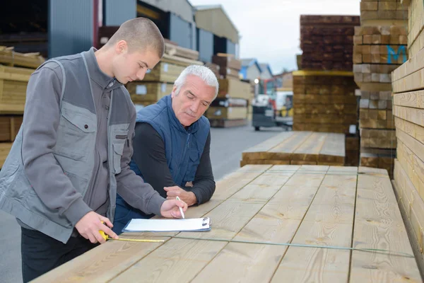 Homens olhando para a área de transferência e medição de madeira — Fotografia de Stock