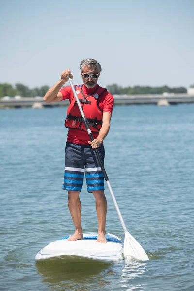 Homem desfrutando de um passeio no lago com paddleboard — Fotografia de Stock