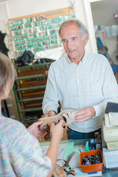 Cobbler dealing with customer — Stock Photo, Image