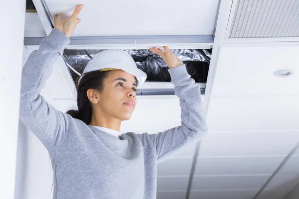Woman replacing ceiling panel — Stock Photo, Image