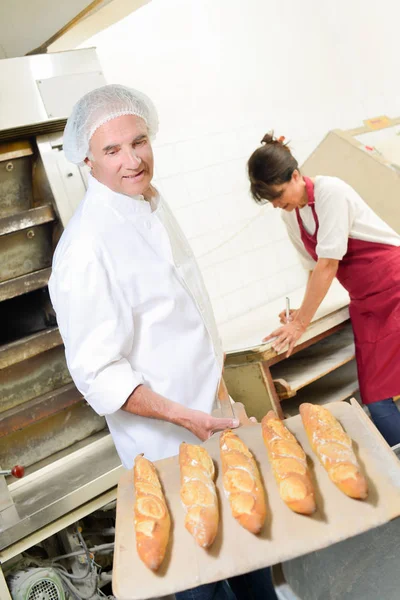 Baker with baguettes and apron — Stock Photo, Image