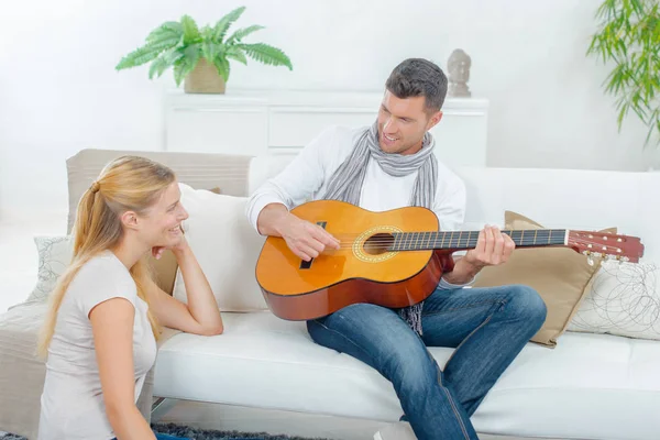 Мужчина играет на гитаре с женщиной — стоковое фото