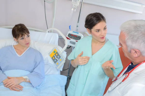 Paciente em cama de hospital, equipe médica em discussão — Fotografia de Stock