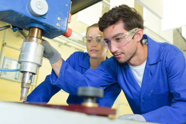 Ernsthafte Auszubildende konzentrierten sich auf das Bohren von Metallteilen mit professionellen Maschinen — Stockfoto