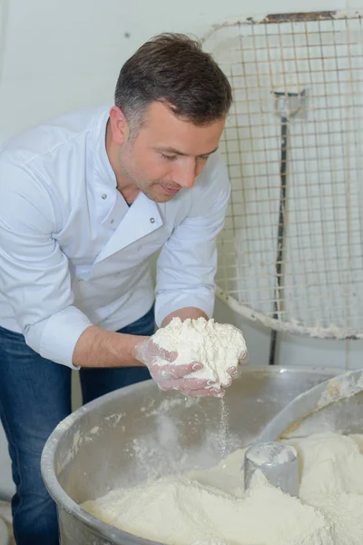 Chef con una manciata di farina sopra mixer industriale — Foto Stock