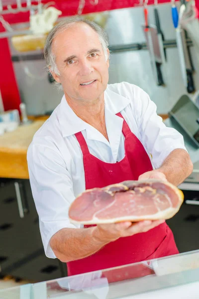 Carnicero sosteniendo articulación de jamón curado —  Fotos de Stock