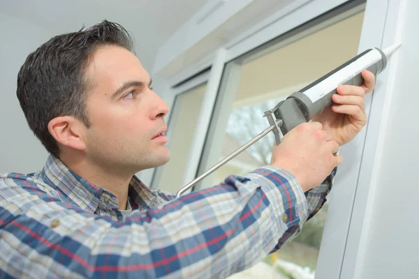 Bauarbeiter versiegelt Fenster im Haus — Stockfoto