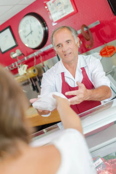 Butcher serving customer over counter — Stock Photo, Image