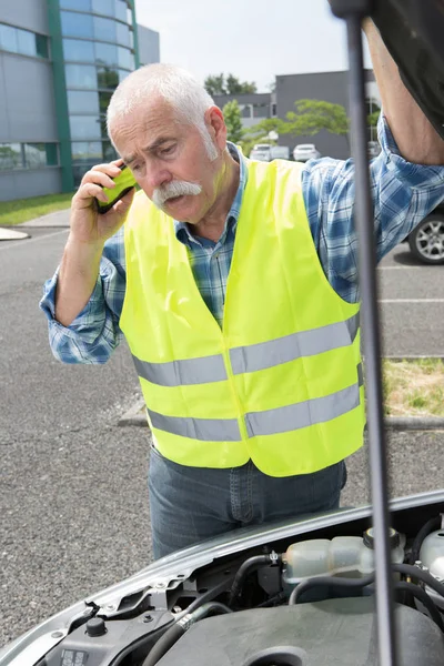 Uomo anziano al telefono guardando la sua auto rotta — Foto Stock