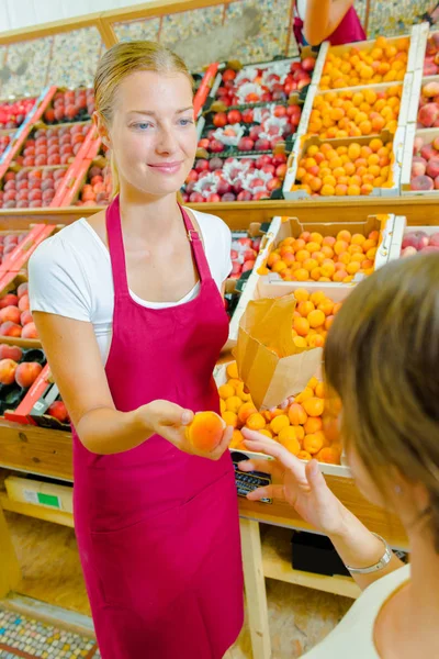Giving an orange to a customer — Stock Photo, Image